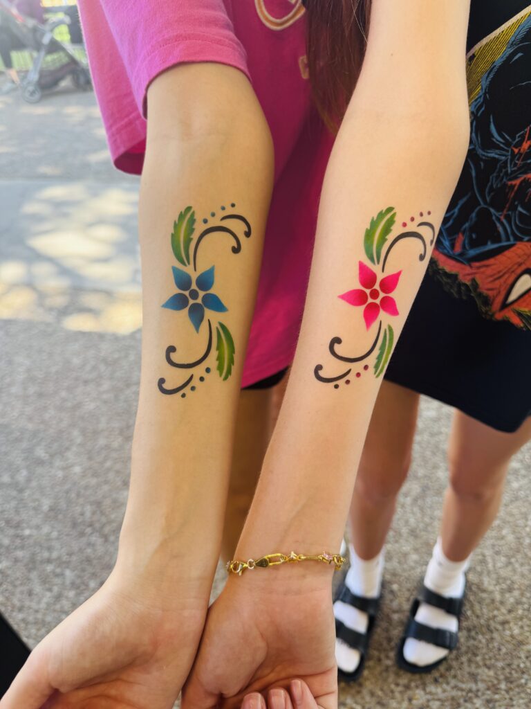 Matching floral airbrush tattoos on two forearms
