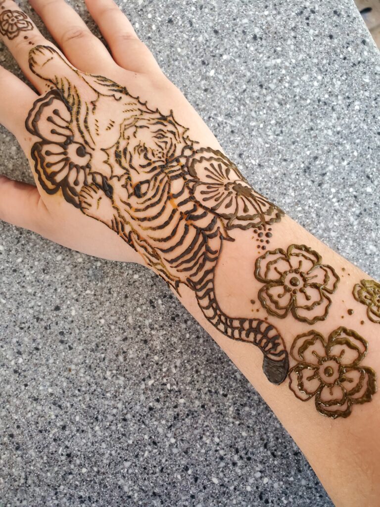 Henna tattoo of a tiger and flowers on a forearm